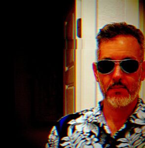 Portrait of DJ SlumberMachine with sunglasses, short hair, short grey beard